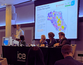 Barry presenting, stood infront of a map of Yorkshire, from behind a table on a stage. 4 others are also sat at the table.