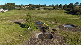 Digger in field working on flood management.