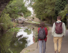 A man and woman walking down a paved riverside path