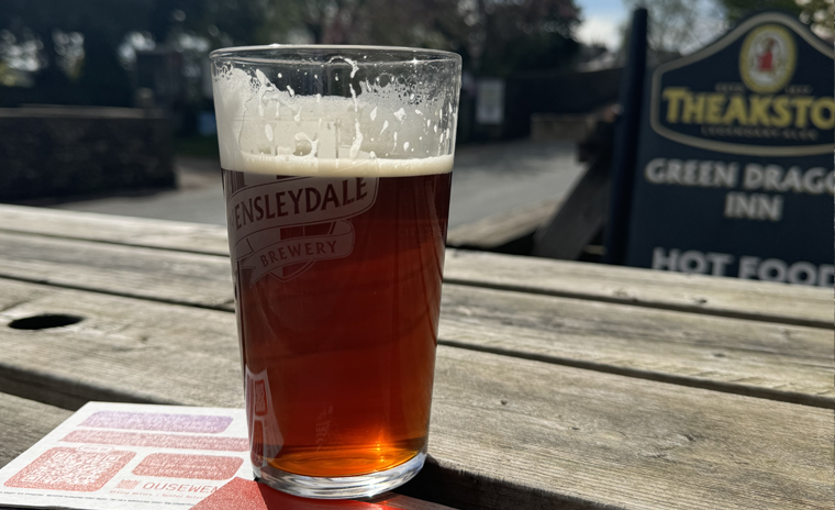 Pint of beer on a printed beer mat on an picnic table